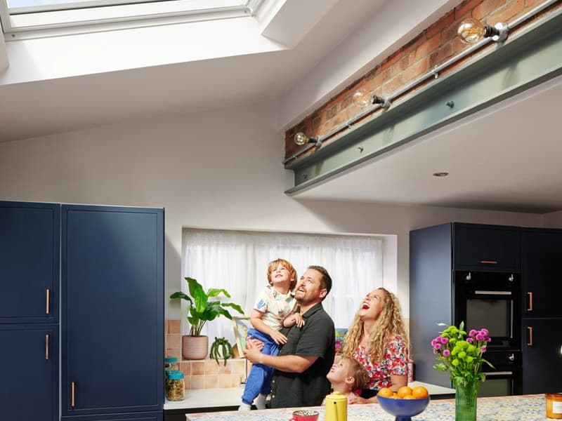 A family in their kitchen in the morning, daylight coming through the roof window above them.