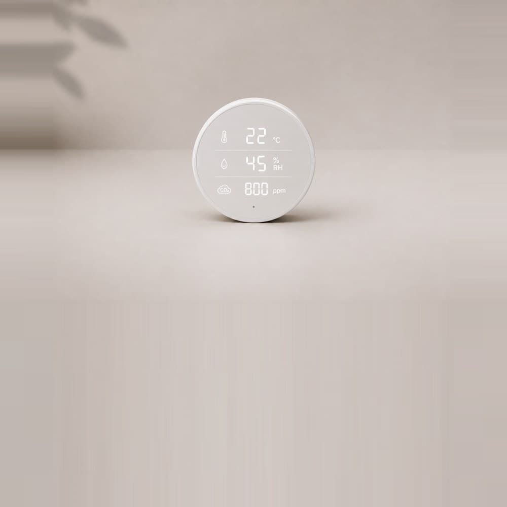 A round white room sensor showing twenty two degrees, forty five percent humidity and eight hundred parts per million of carbon dioxide.